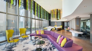 A modern lounge area with a purple sofa, yellow chairs, and a glass wall with vertical blinds. - W Kuala Lumpur (Kuala Lumpur)