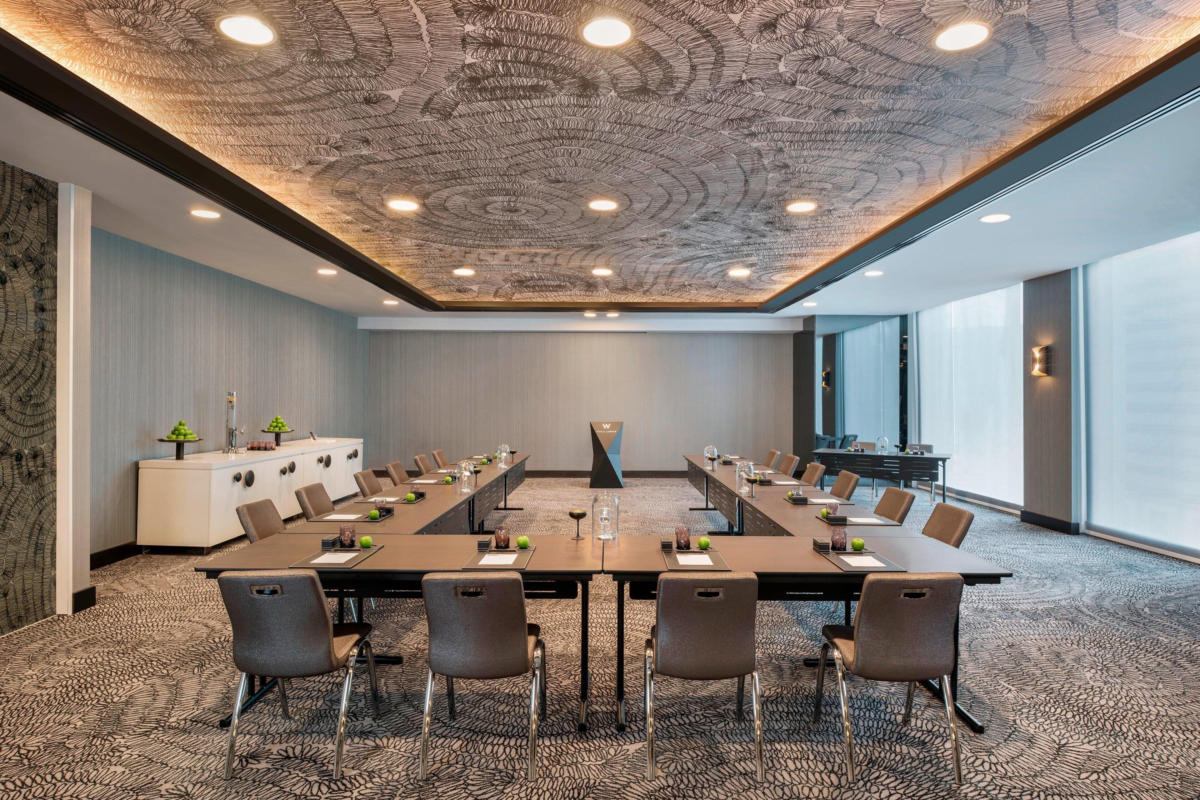 A conference room with a long table, chairs, a white cabinet, and a large window.