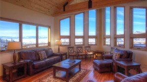 A spacious living room with leather sofas, a coffee table, and a view of a snowy landscape through large windows.