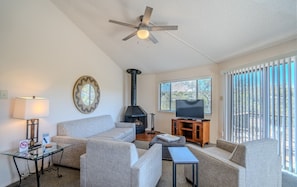 A living room with a sofa, a television, a fireplace, and a ceiling fan.
