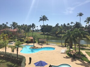 A resort with a swimming pool, palm trees, and a golf course.