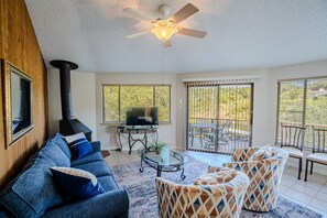 A living room with a sofa, armchairs, a television, a fireplace, and a balcony with outdoor furniture. - Golden Rod #2 - Waterside Escape with Resort Pool (Lakeway)