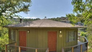 A small, single-story cabin with a wooden deck and a covered porch.