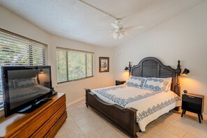 A bedroom with a bed, a television on a wooden dresser, a ceiling fan, and two bedside lamps. - Golden Rod #2 - Waterside Escape with Resort Pool (Lakeway)
