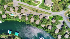 An aerial view of a lakeside property with a swimming area, circular docks, and a road. - Luxury Lakehouse in striking distance to Austin with pool [#8 Rainbow Cactus] (Lakeway)