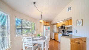 A kitchen with wooden cabinets, a dining table with chairs, and a hanging light fixture. - Luxury Lakehouse in striking distance to Austin with pool [#8 Rainbow Cactus] (Lakeway)