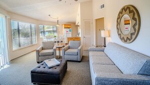 A living room with a sofa, two armchairs, a coffee table, a ceiling fan, and a kitchen area in the background. - Luxury Lakehouse in striking distance to Austin with pool [#8 Rainbow Cactus] (Lakeway)