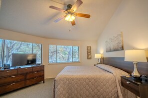 A bedroom with a bed, a desk with a television, a ceiling fan, and a window with blinds. - Rainbow Cactus #8 - Lakefront Oasis with Pool Access (Lakeway)