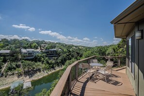 A wooden deck with outdoor furniture overlooking a river and a forested area.