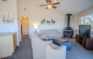 A living room with a sofa, a television, a fireplace, and artwork on the wall.