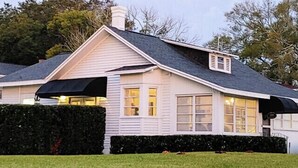 Ein eingeschossiges Haus mit Satteldach, einer Veranda und einem Schornstein.