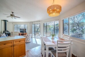 A modern kitchen with a stove, dining area with a table and chairs, and a ceiling fan.