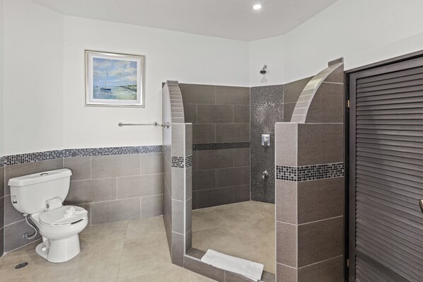 Un baño moderno con inodoro, ducha con pared de azulejos y puerta con textura.