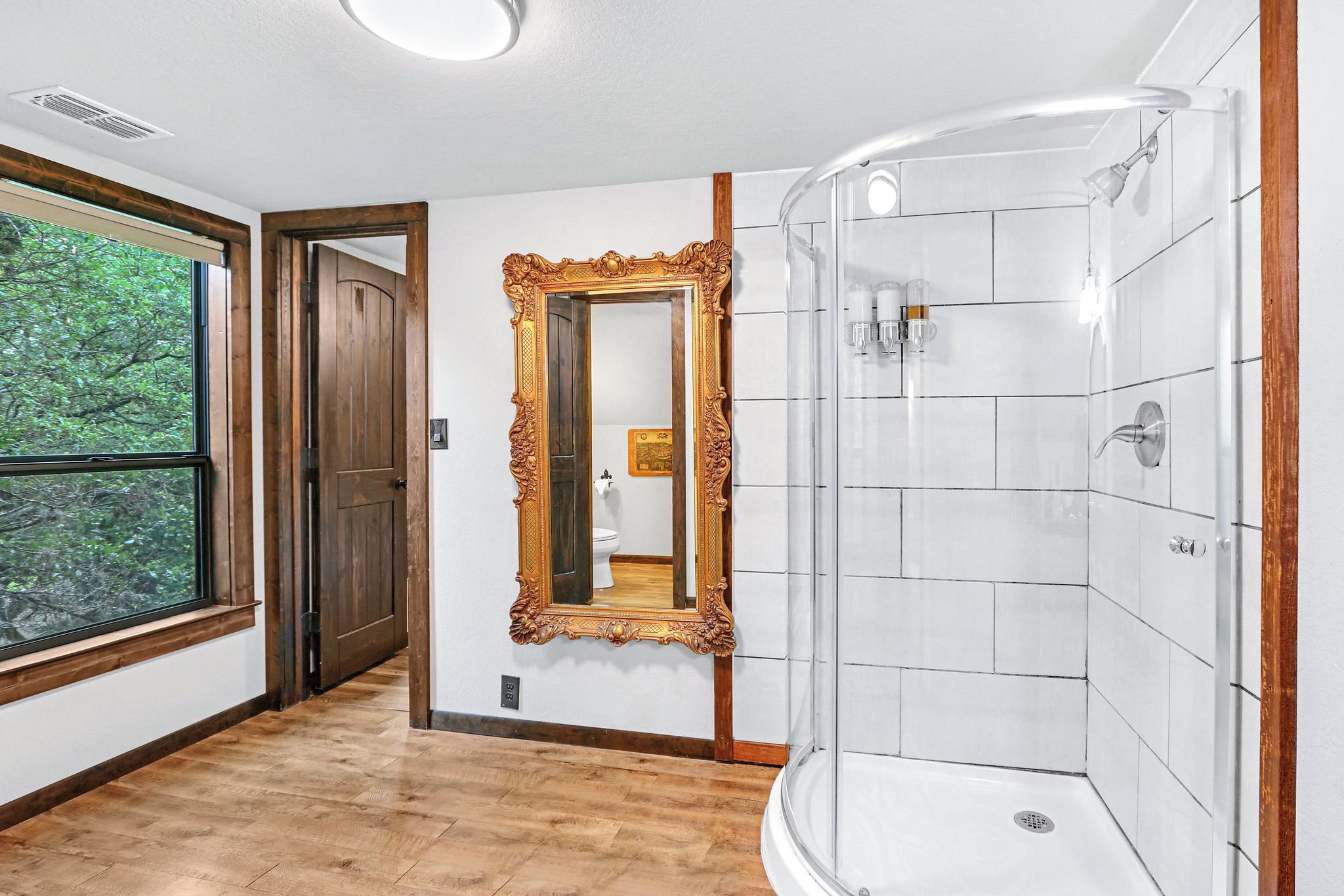Un baño con ducha, un espejo grande y una ventana con persianas.