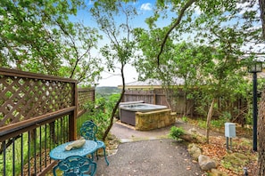 A patio area with a hot tub, a wooden fence, and a view of the landscape.