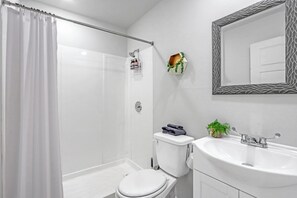 Un baño moderno con ducha, inodoro, lavabo y espejo.