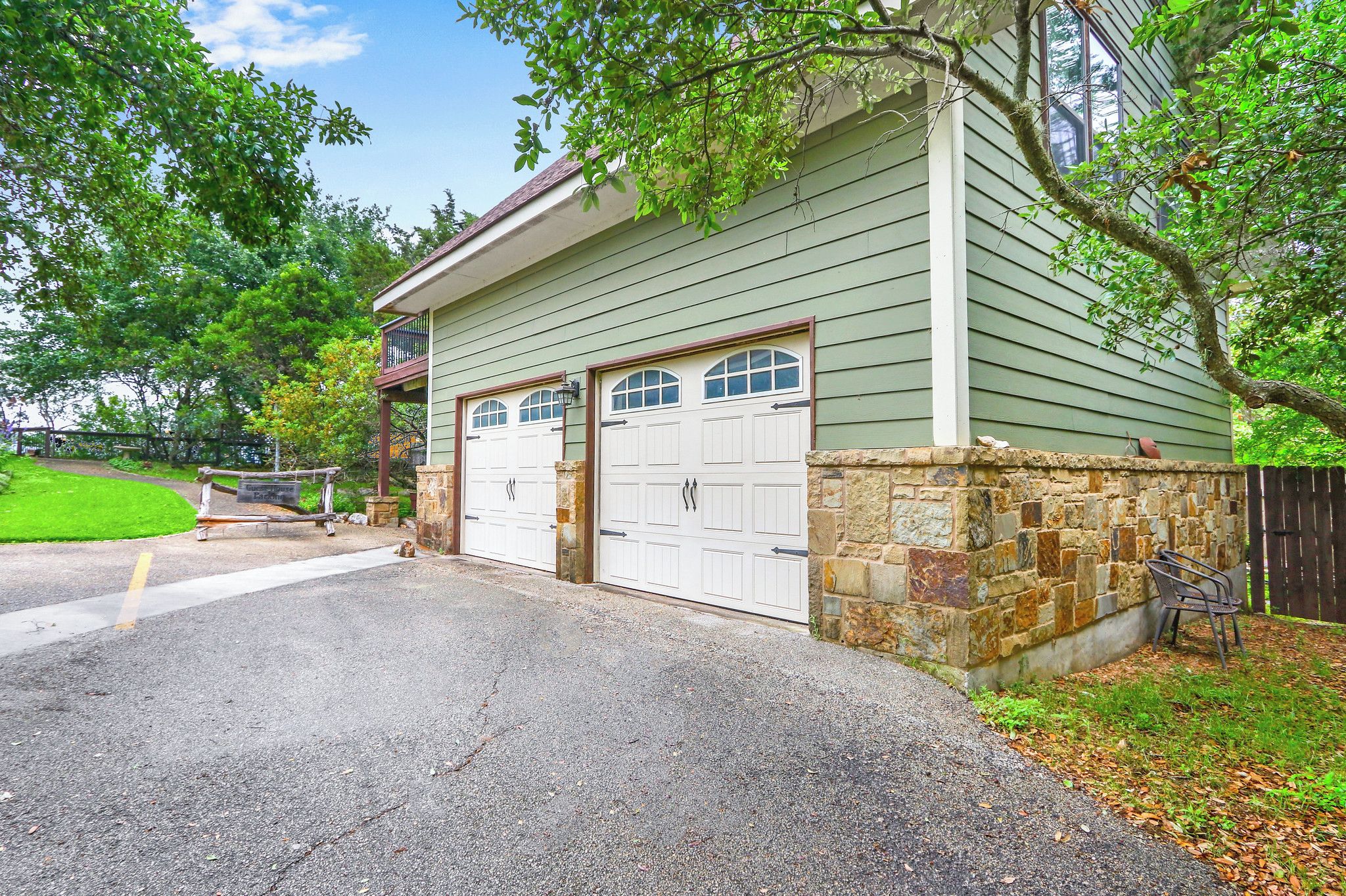 A two-story house with a garage, stone foundation, and a small porch.