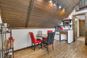 Un comedor con techo de madera, una mesa redonda y sillas rojas.
