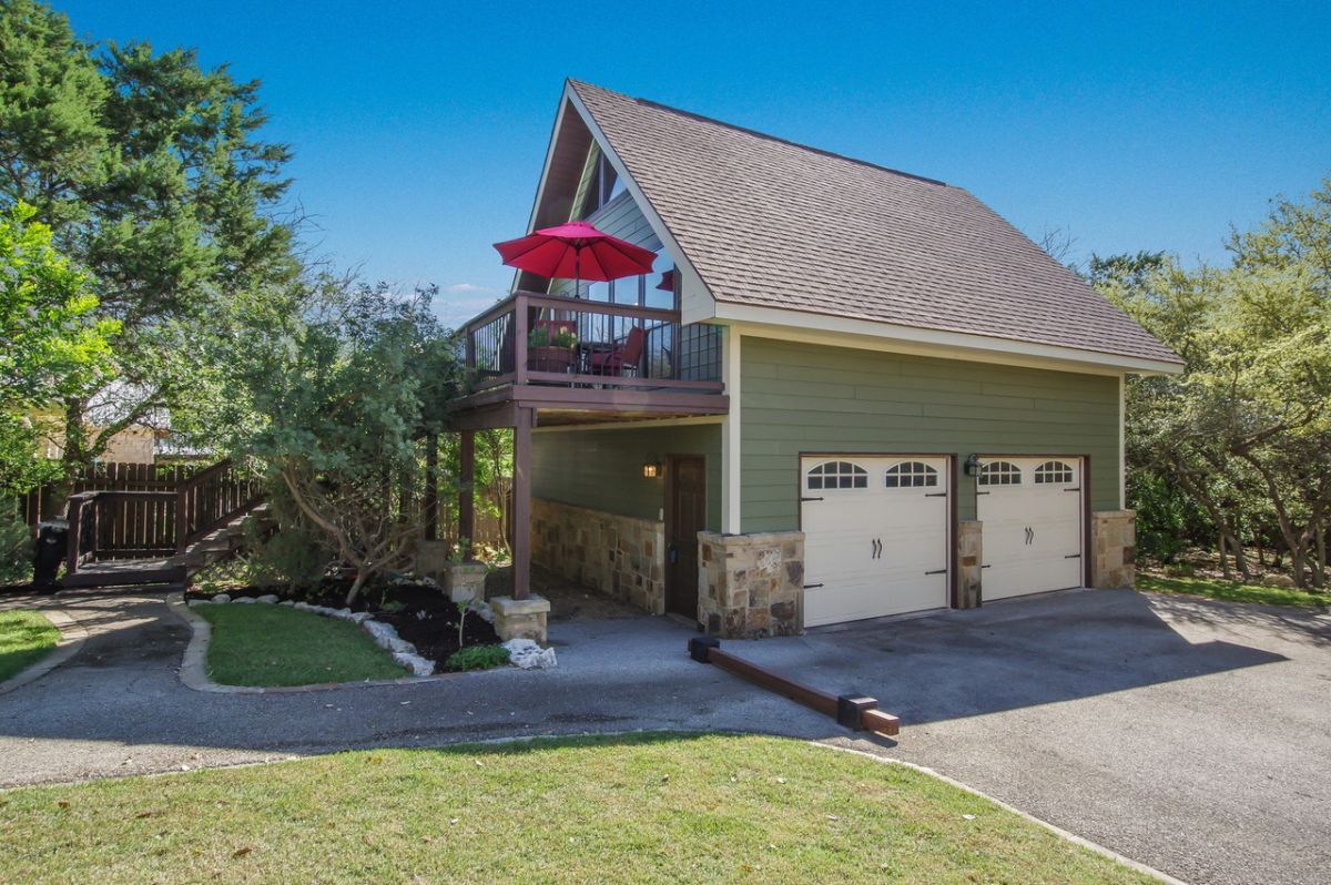A two-story house with a balcony, a garage, and a well-maintained lawn.