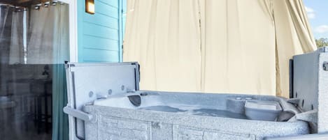 Una bañera de hidromasaje con revestimiento de piedra, puerta de cristal y cortina color beige.