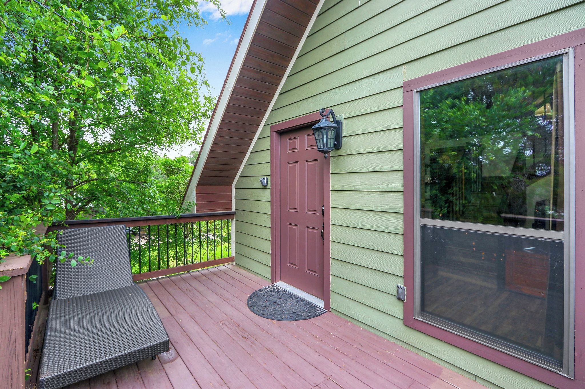 A wooden deck with a red door and a large window.