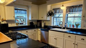 A kitchen with white cabinets, a black countertop, a stove, and a sink.
