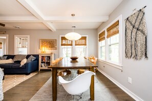 A dining area with a wooden table, white chairs, and a chandelier.
