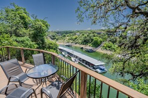 Een terras met zitplaatsen buiten, met uitzicht op een rivier met boten.