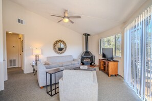Un salon comprenant un canapé, une table basse, un téléviseur, une cheminée et un ventilateur de plafond.