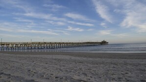 Eine Steg, der sich ins Meer erstreckt, mit blauem Himmel darüber.