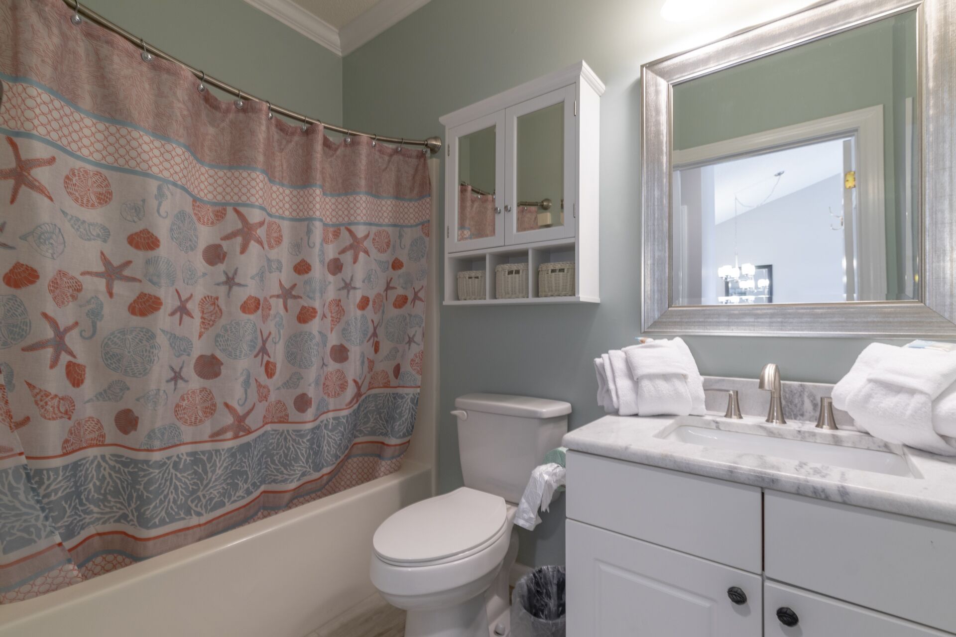 A bathroom with a bathtub, toilet, and vanity with a mirror.