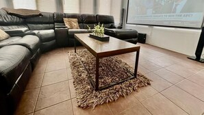 A living room with a sectional sofa, a coffee table, and a projector screen displaying a news article. - Luxurious Franklin Experience! 5min To Downtown   (Franklin)