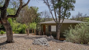 A small, single-story building with a porch and a gravel driveway. - Lakefront Retreat with Pool & Hot Tub [#1 Ocotillo] (Lakeway)