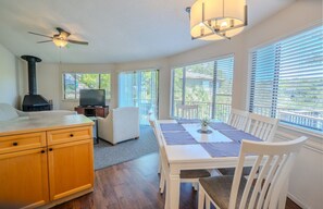 A kitchen with a stove, a dining table with chairs, and a ceiling fan. - Acacia #17 - Secluded Treehouse with Resort Hot Tub (Lakeway)