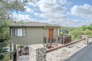 A single-story cabin with a front door, a small porch, and a stone retaining wall. - Texas Thistle #9 - Waterside Villa with Spa Amenities (Lakeway)