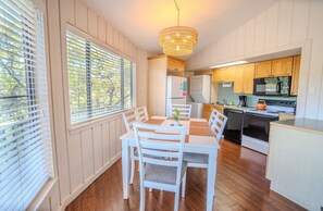 A compact kitchen with white cabinets, a microwave, stove, and a small dining area with a table and chairs.