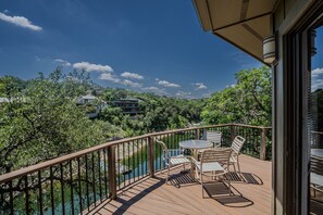 A wooden deck with outdoor furniture overlooking a body of water and a forested area. - Texas Thistle #9 - Waterside Villa with Spa Amenities (Lakeway)