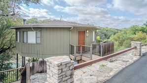 A small, single-story cabin with a wooden deck and stone walls, located in a wooded area with a clear sky. - Stunning Waterside holiday home between Austin & San Antonio [#9 Texas Thistle] (Lakeway)
