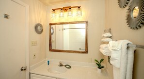 Ein Badezimmer mit Waschbecken, Spiegel, Handtuchhalter und dekorativen Wandleuchten.