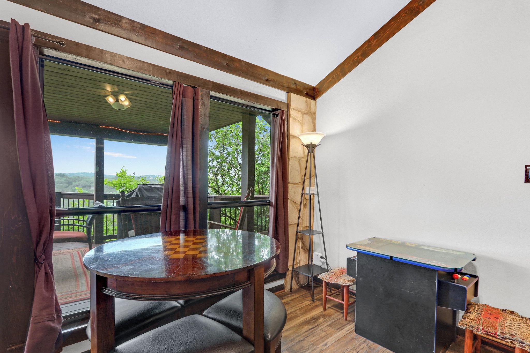Una habitación con una mesa redonda, sillas, un taburete pequeño, una mesa de ping pong y vistas amplias a través de grandes ventanales.