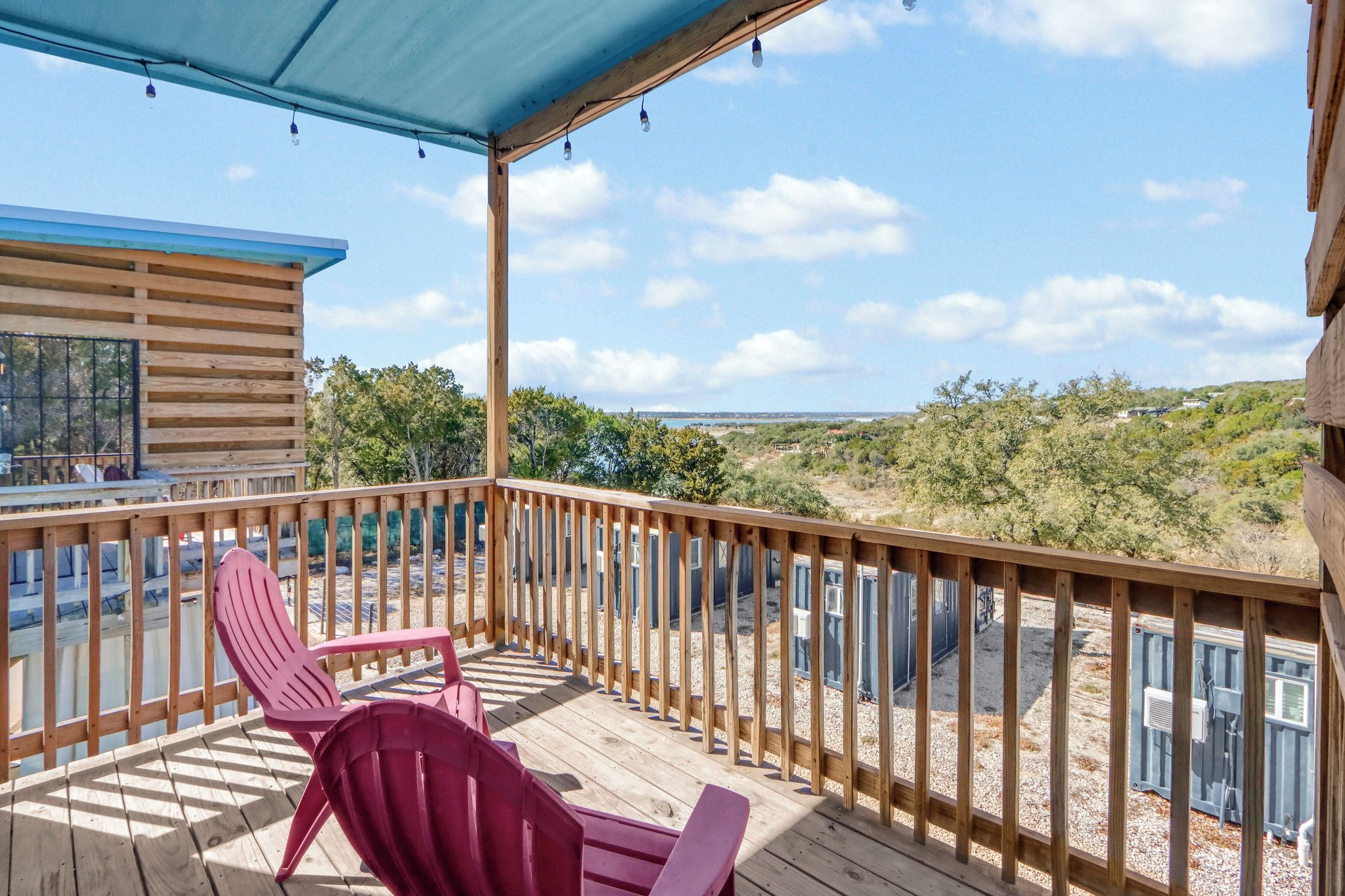 Un terrazza in legno con sedie, una zona riparata e vista su un paesaggio collinare.