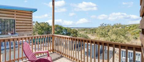 Un terrazza in legno con sedie, una zona riparata e vista su un paesaggio collinare.