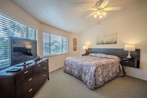 A bedroom with a bed, a television on a dresser, a ceiling fan, and a window with blinds. - Texas Thistle #10 - Lakefront Villa with Resort Pool (Lakeway)