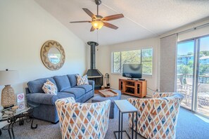A living room with a sofa, TV, fireplace, and a balcony with outdoor furniture. - Primrose #6 - Lake View Retreat with Hot Tub Access (Lakeway)