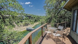 A wooden deck with a table and chairs, overlooking a river and greenery. - Gorgeous Waterside Holiday Rental in Lakeway with pool/jacuzzi [#6 Primrose] (Lakeway)