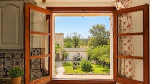 A kitchen with a window view of a garden, a tiled backsplash, and a wooden cabinet. - Can Pou - private pool - wifi - AACC (S'Aranjassa)