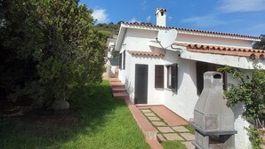 Ein Haus mit Ziegeldach, Schornstein und Grill im Garten.