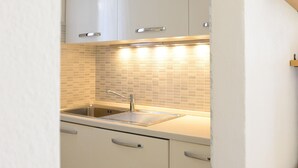 Una cocina moderna con armarios blancos, salpicadero de azulejos y pileta de acero inoxidable.