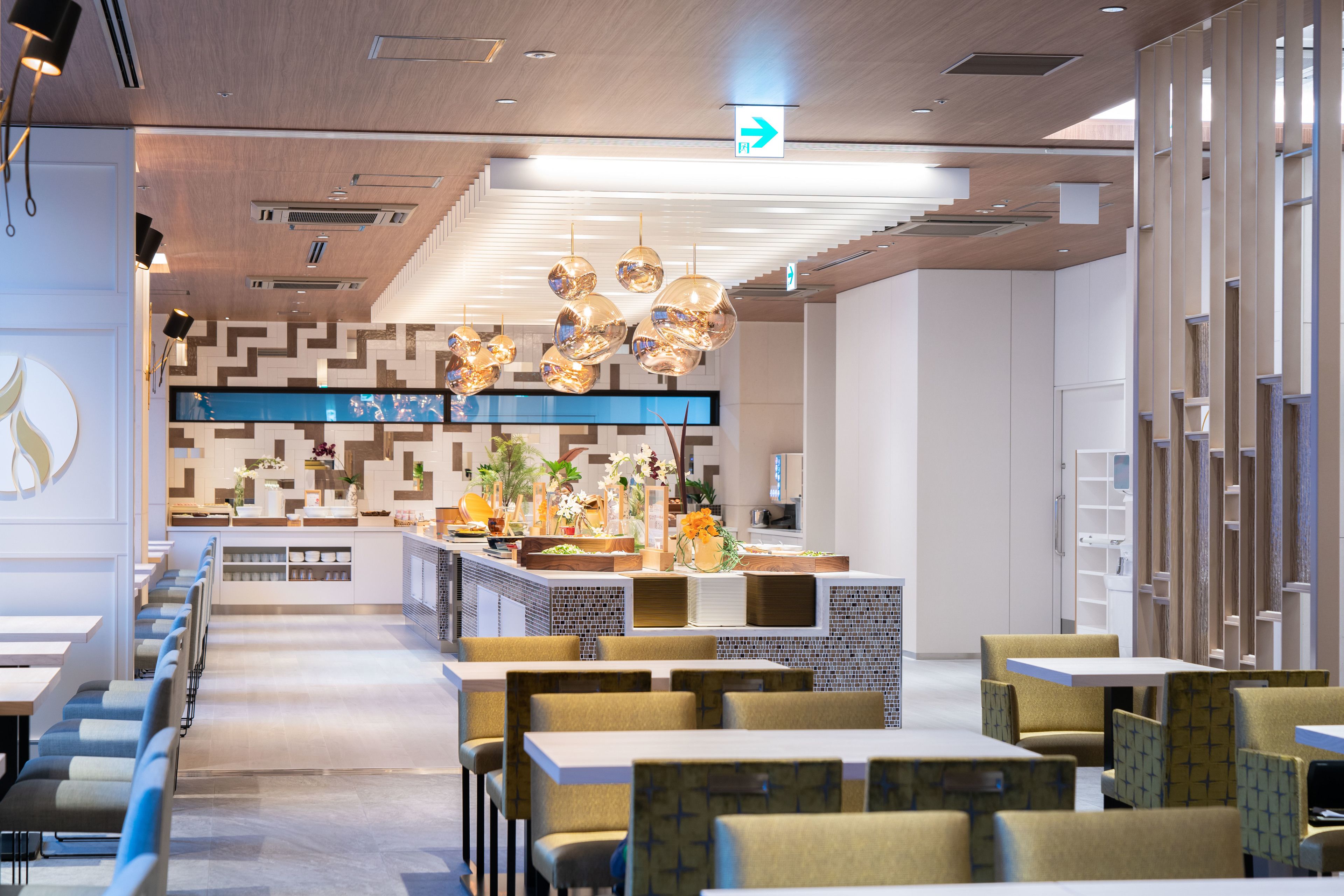 A modern restaurant with a long counter, booths, and hanging spherical light fixtures.