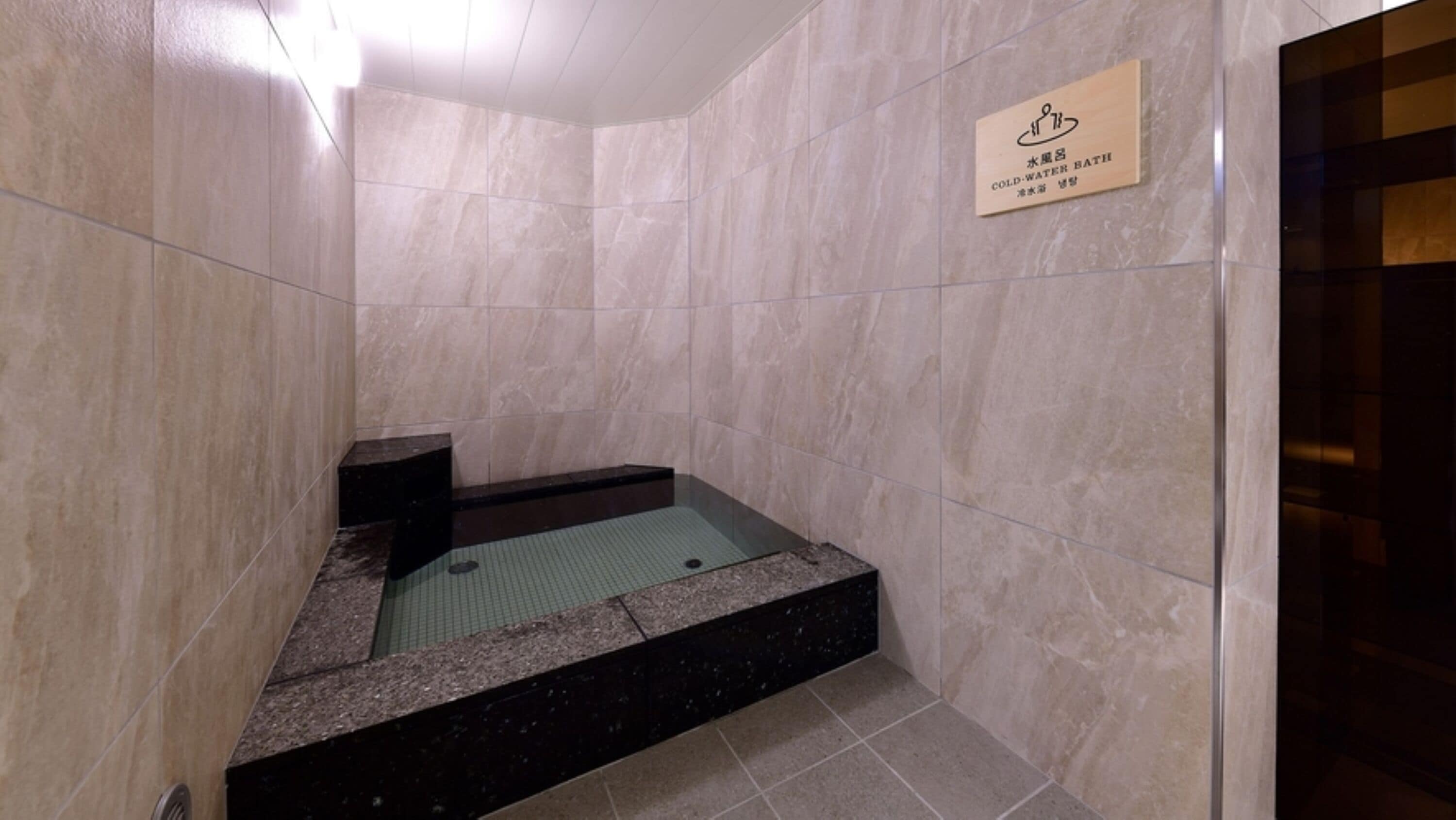 A small, enclosed cold-water bath area with a sign indicating its purpose.